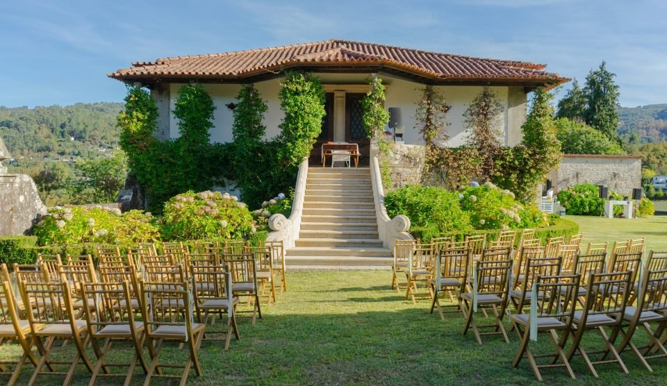 A white-gabled Cape Dutch manor with stone steps and garden chairs set for a ceremony